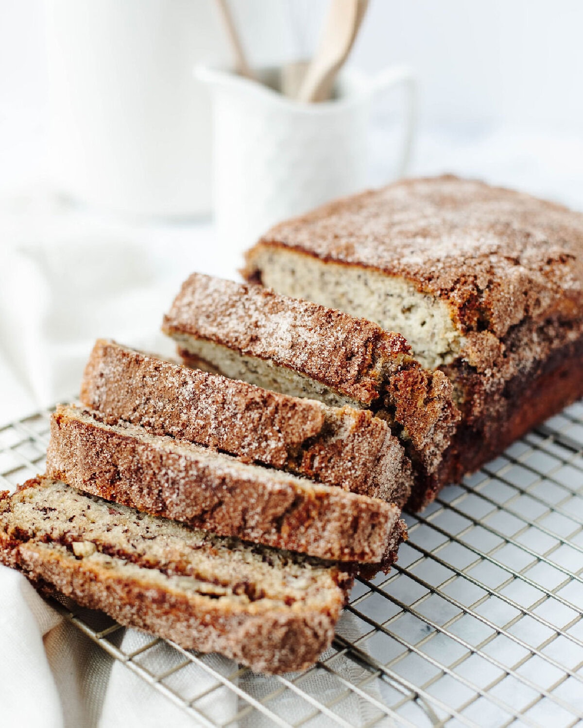 a side view of a baked loaf of snickerdoodle banana quick bread on a wire rack.