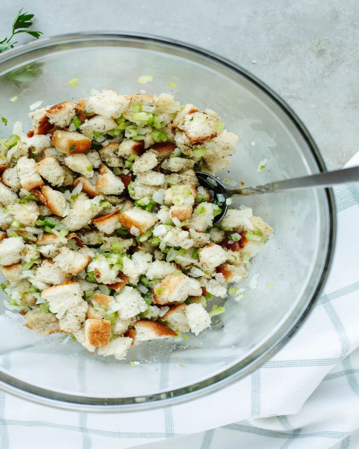 bread cubes tossed with sauteed onions and celery in a glass mixing bowl.