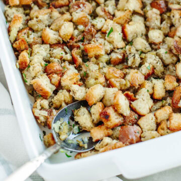 an up close look at homemade stuffing in a white baking dish ready to be served.