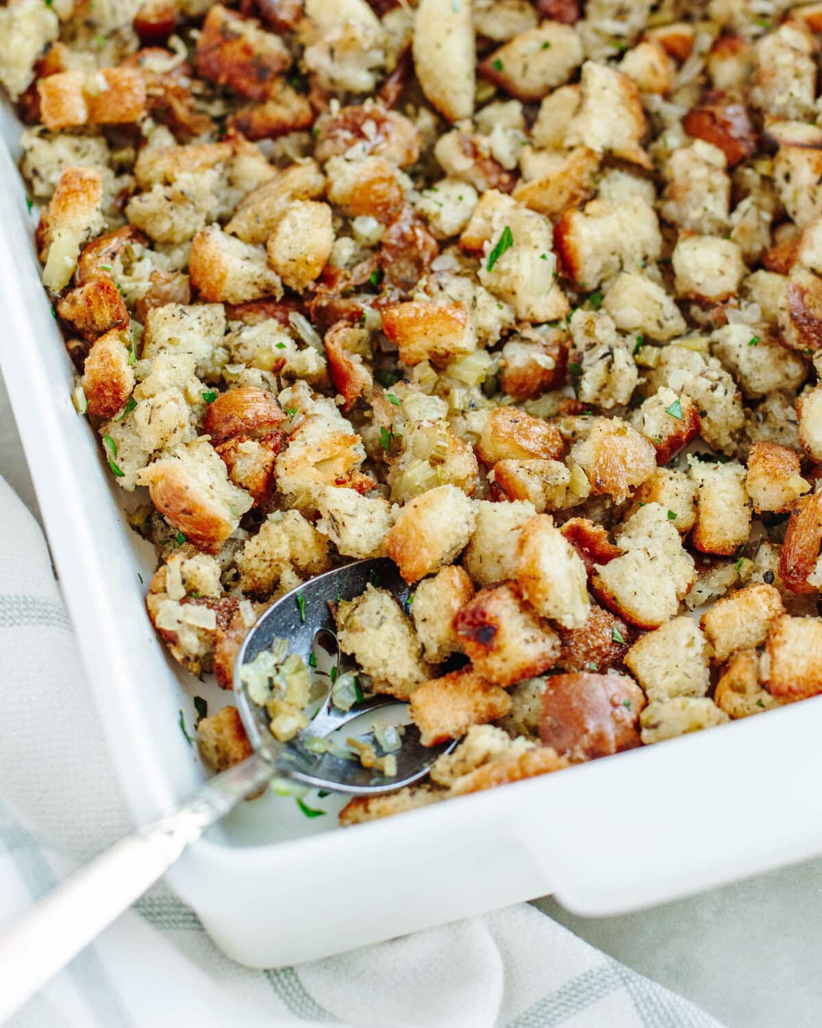 an up close look at homemade stuffing in a white baking dish ready to be served.