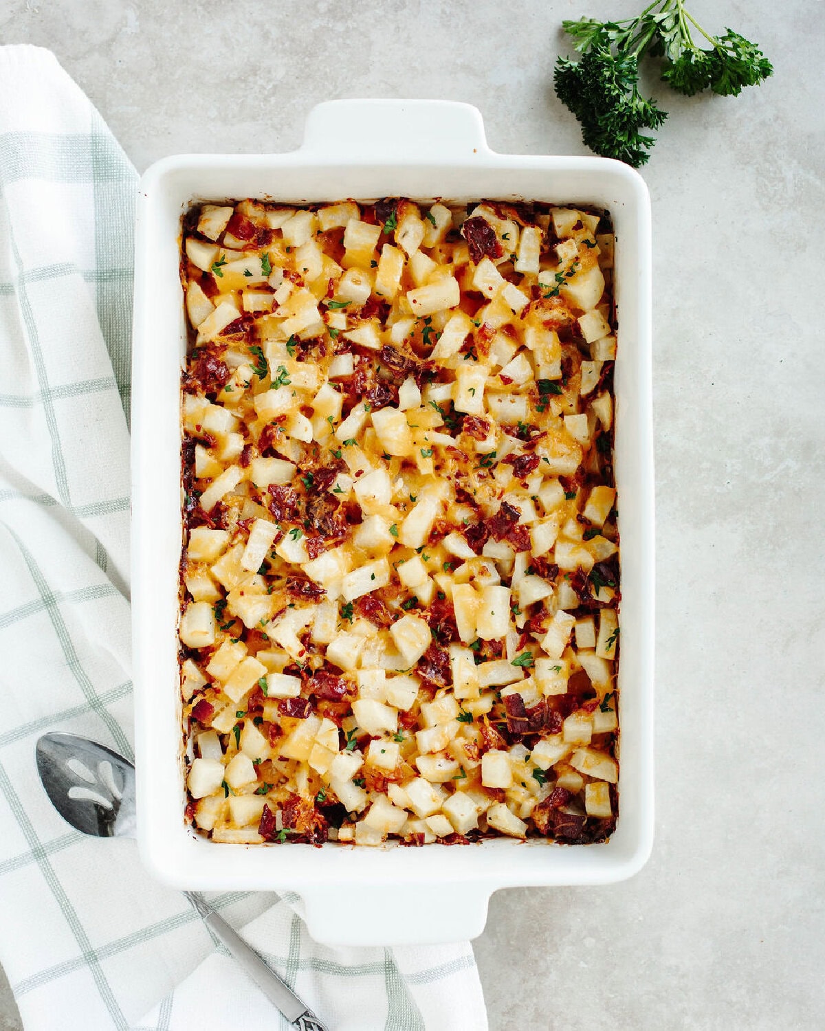 a baked Holiday potato casserole ready to serve from a white 9x13 baking pan.