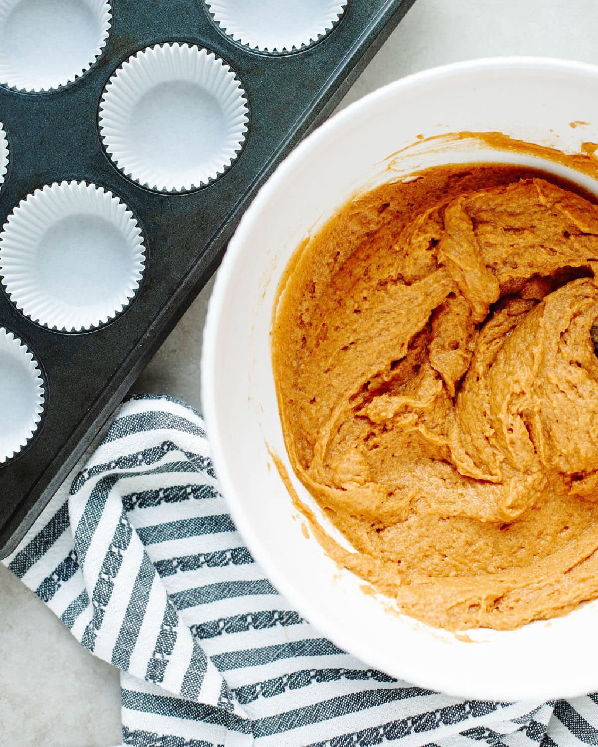 wet ingredients added into dry ingredients in a white mixing bowl to make pumpkin muffins.