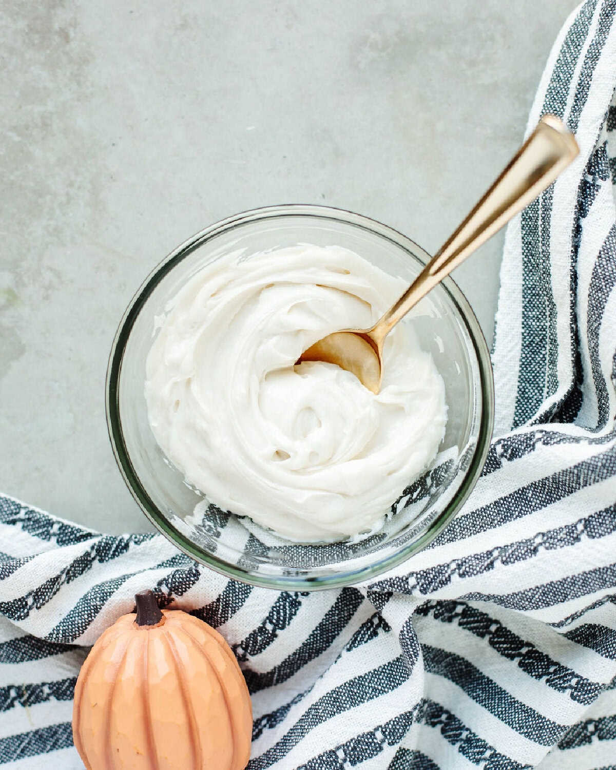 cream cheese filling combined in a glass bowl with a gold spoon.