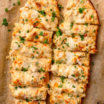 sliced pieces of garlic bread with chopped chicken and creamy Alfredo sauce.