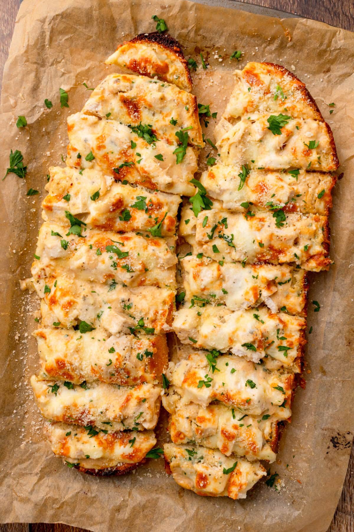 sliced pieces of garlic bread with chopped chicken and creamy Alfredo sauce.