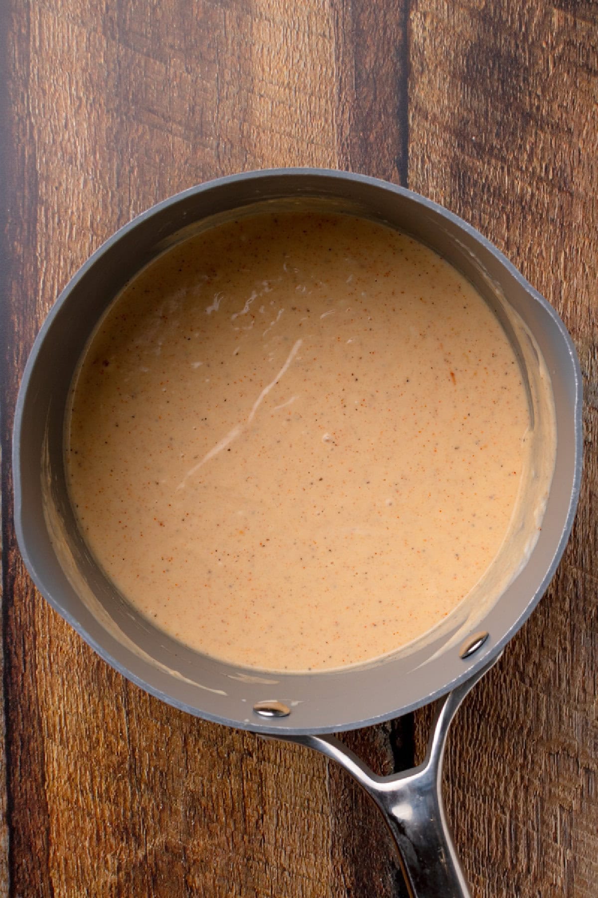 heated Alfredo sauce in a skillet with additional butter, Parmesan, onion powder, paprika, salt, and pepper.