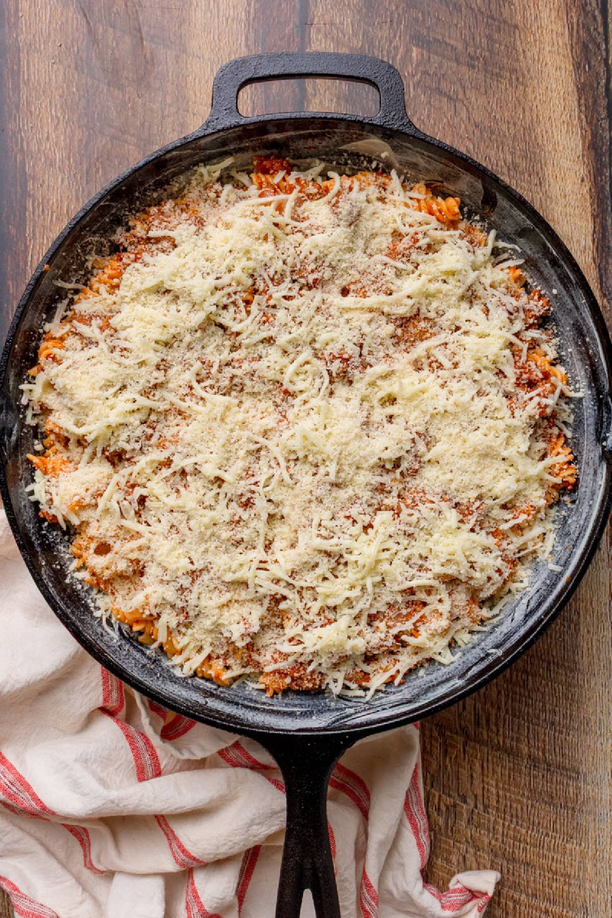 grated Parmesan on top of a layered pasta in a cast iron skillet.