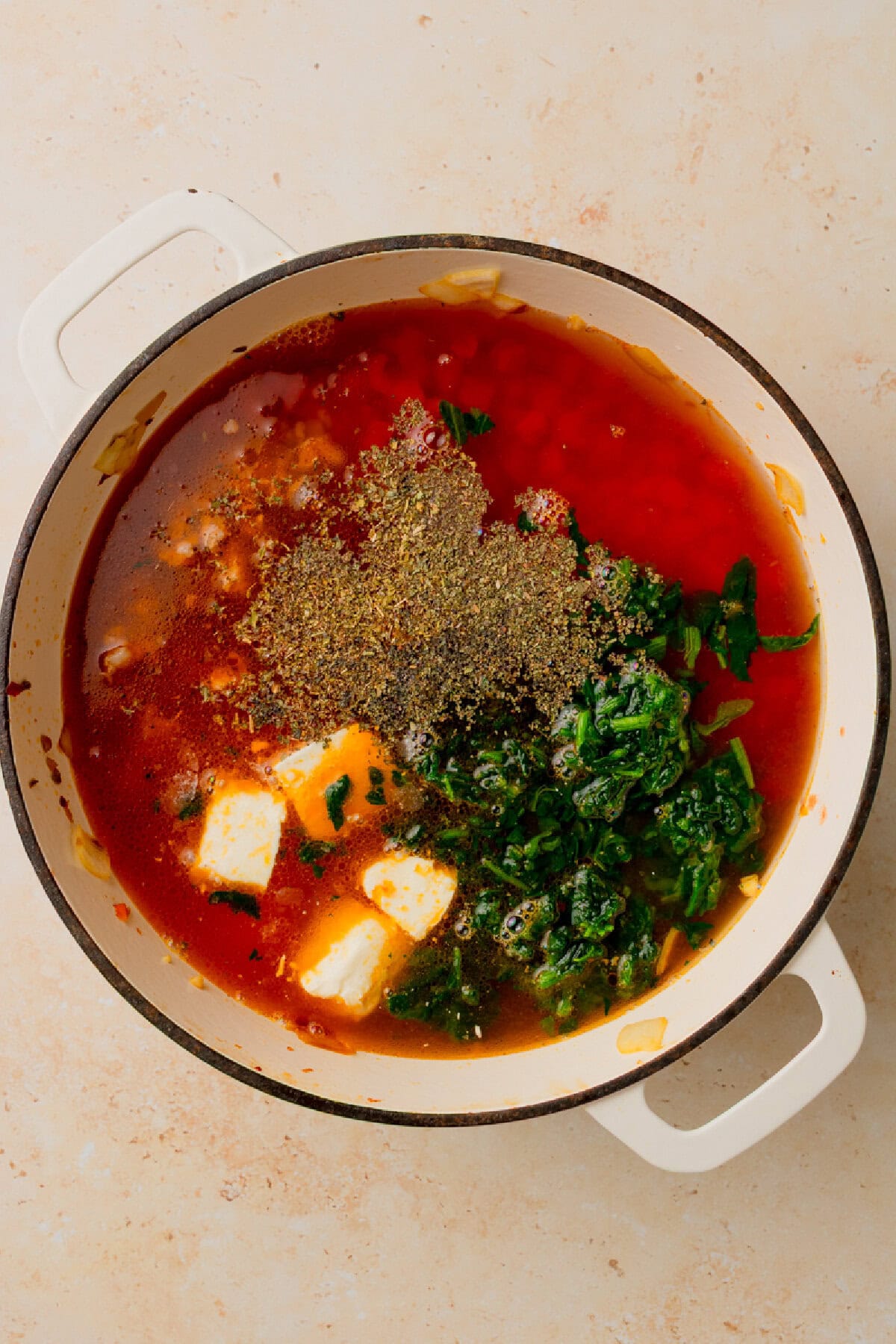 broth, seasonings, and cream cheese added to a Dutch oven to simmer.