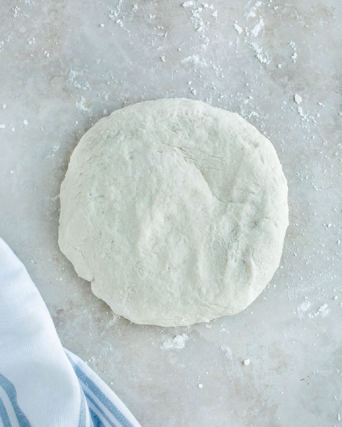 a round flattened ball of dough on a floured surface.