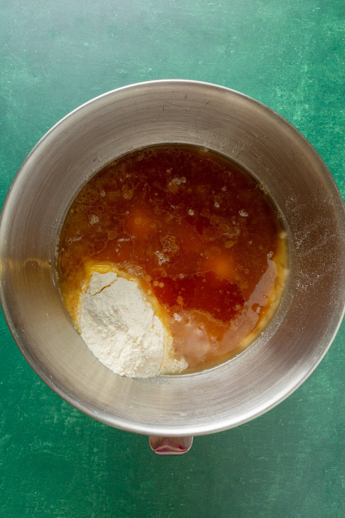wet ingredients added to dry ingredients in a mixing bowl to make a cake.