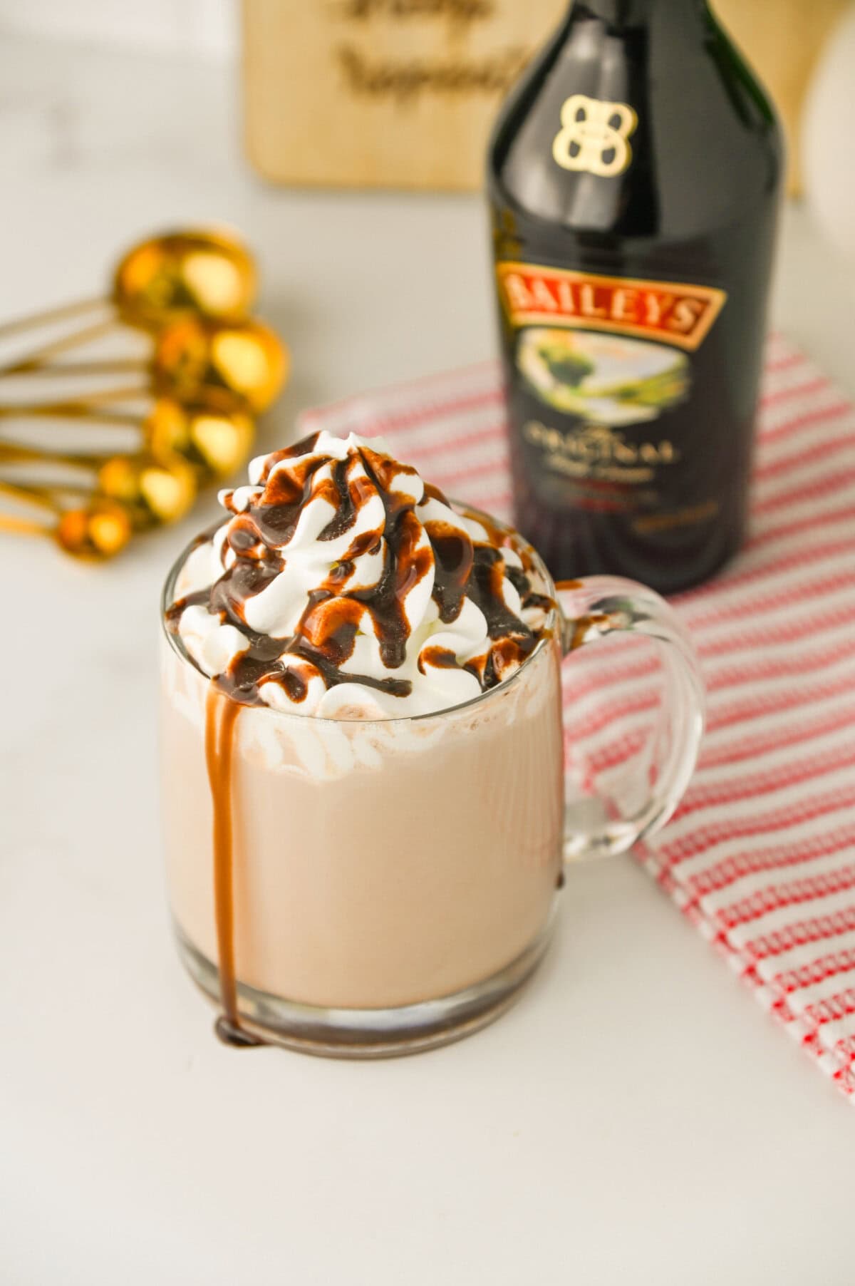 boozy hot cocoa in a glass mug with whipped cream and Hershey sauce.