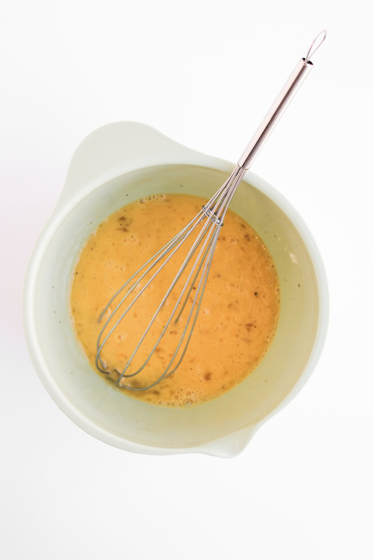 eggs whisked together with milk, salt, and pepper in a mixing bowl.