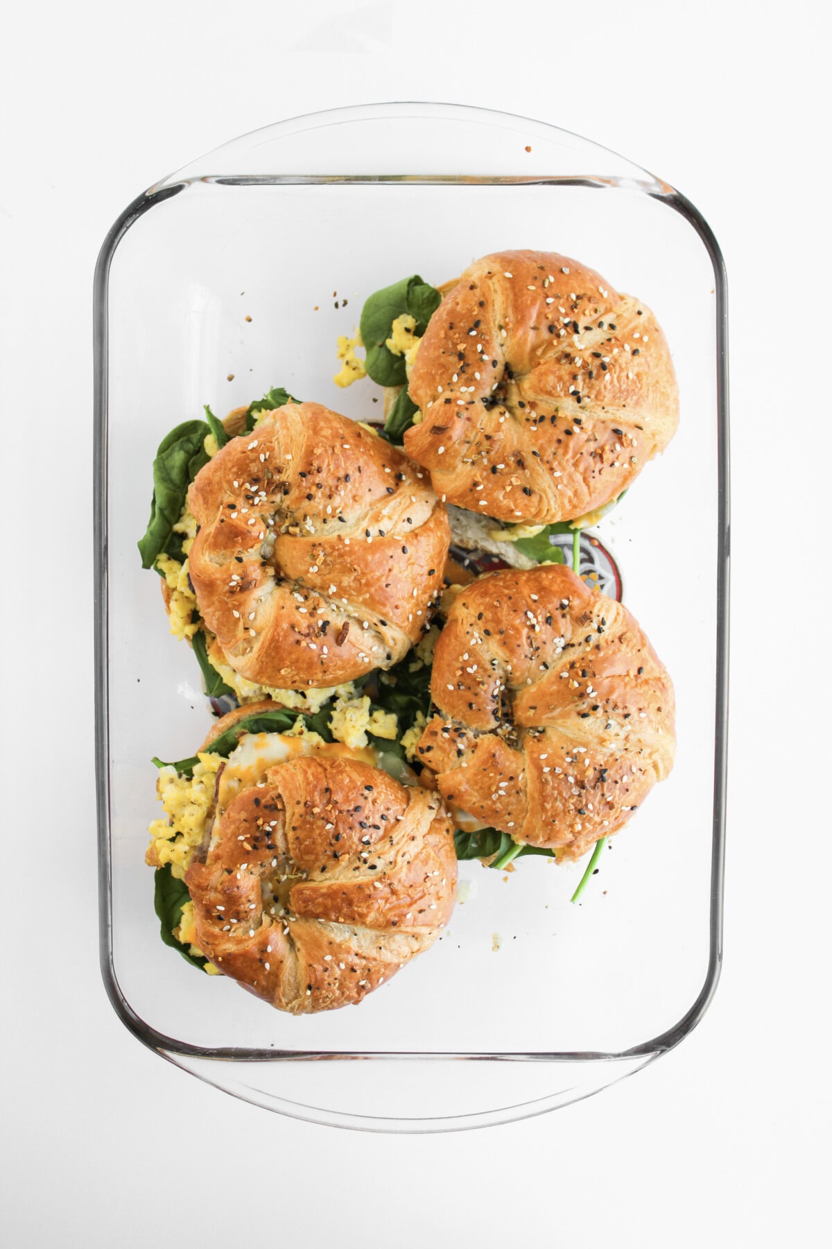 breakfast sandwiches in a glass baking dish ready for the oven.