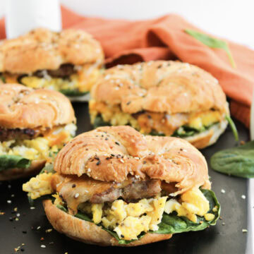 a side view of a sausage, egg, and cheese breakfast sandwich on a black plate.