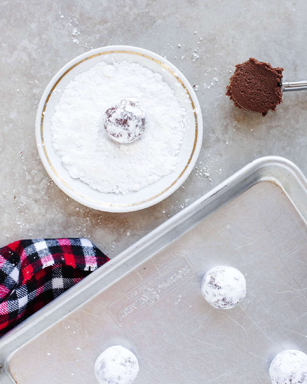cookie dough balls rolled in powdered sugar and placed on a baking sheet.
