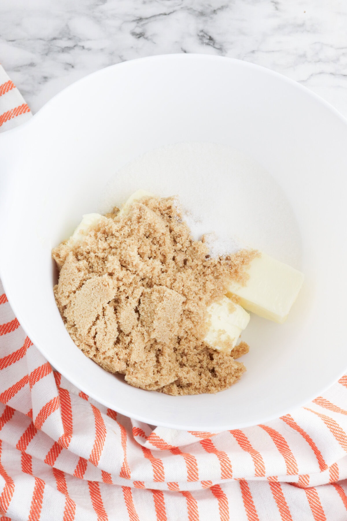 brown sugar, white sugar, and butter creamed together in a white mixing bowl.