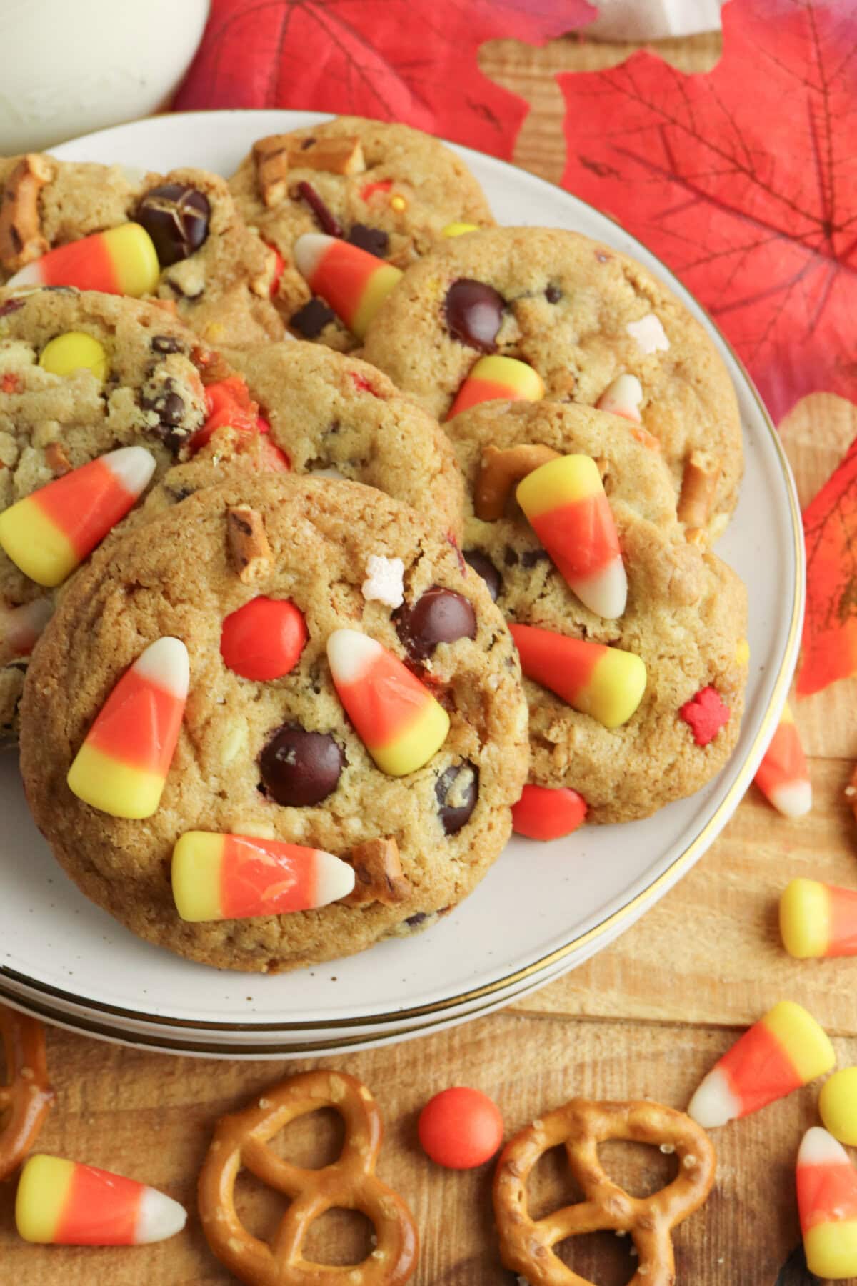 Loaded Fall Harvest Cookies with candy corn and pretzels stacked on a white plate.