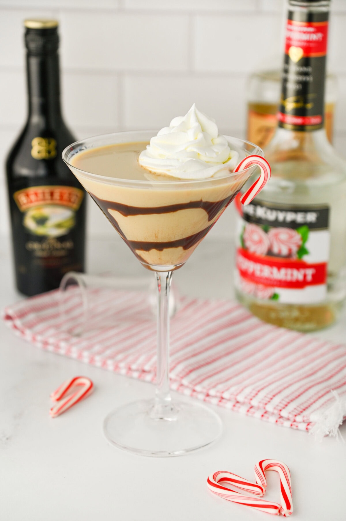 Baileys Peppermint Martini in a martini glass topped with whipped cream and mini candy cane.