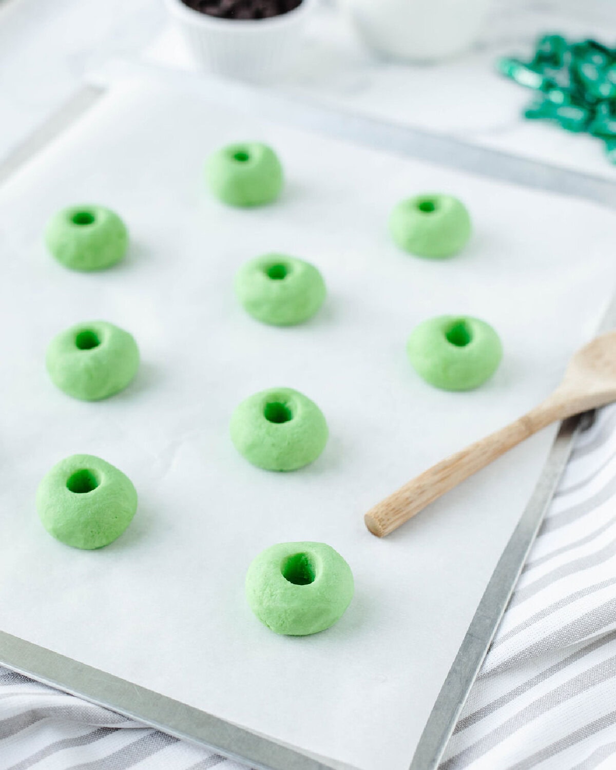 mint cookie dough placed into one inch balls on parchment paper with deep wells for filling.