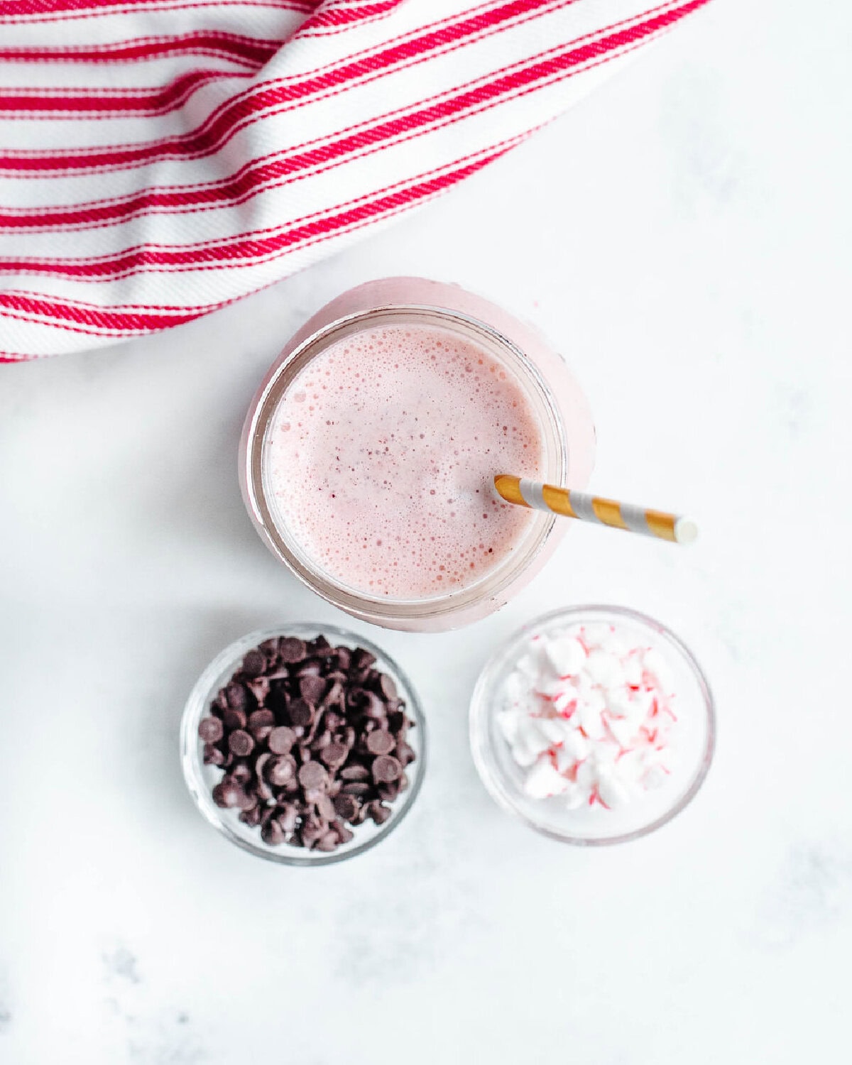 a blended peppermint milkshake ready to top with candy cane and chocolate chips.