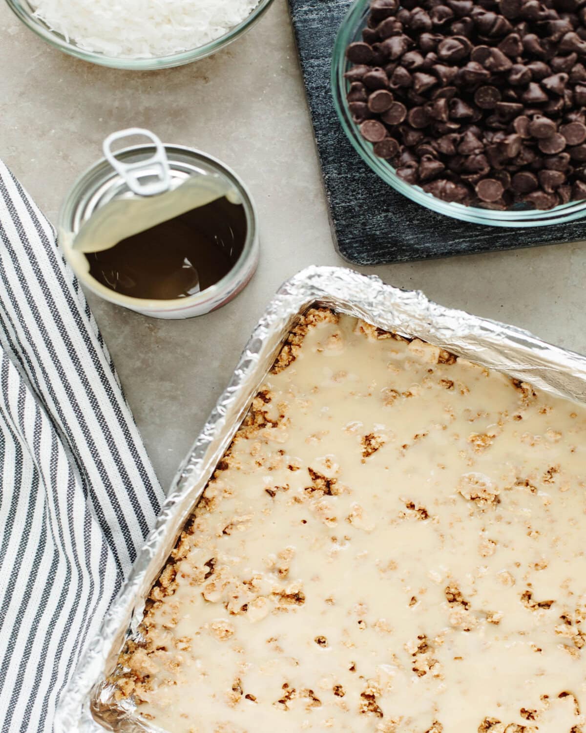 sweetened condensed milk poured on top of a graham cracker crust in a foil lined baking dish.