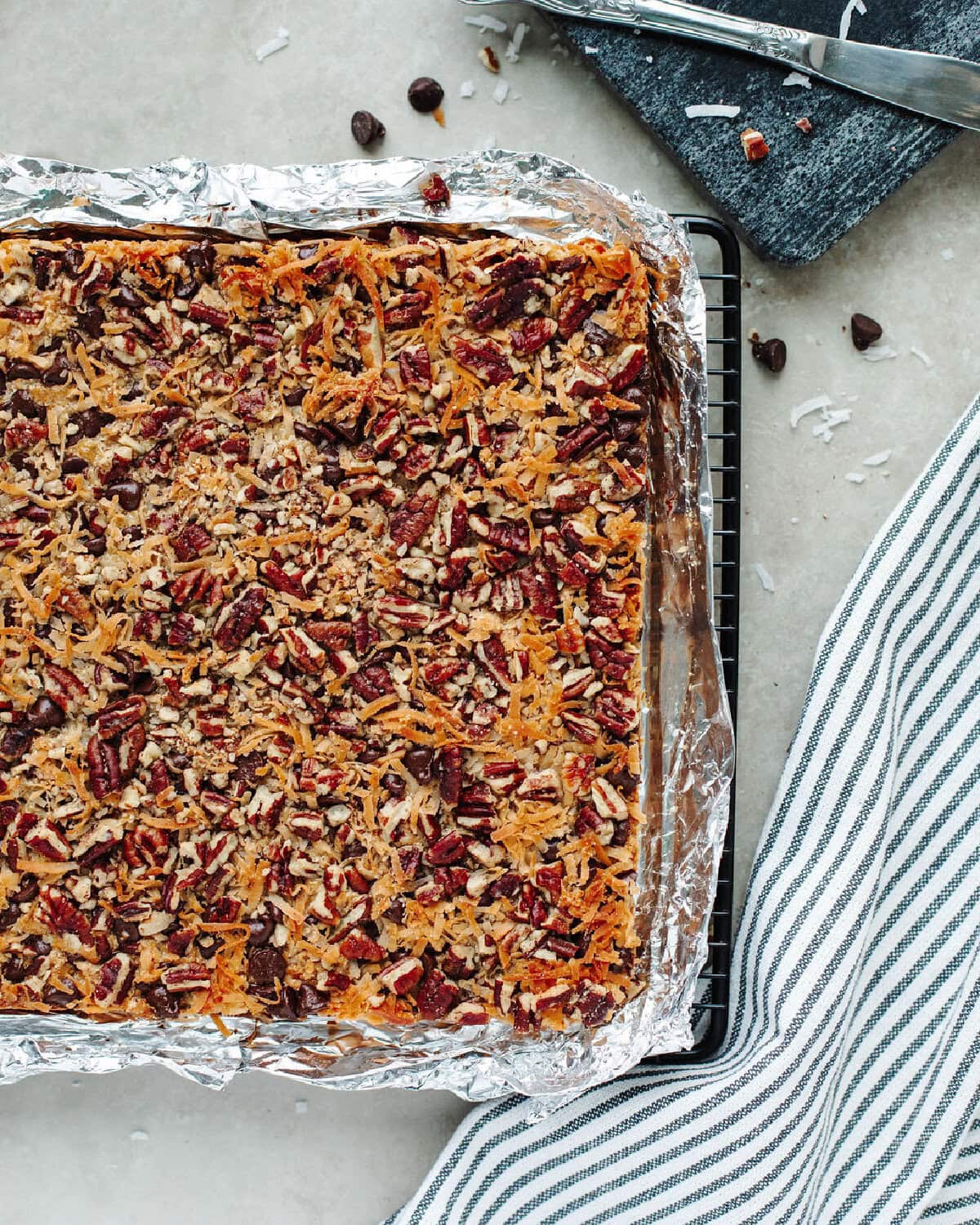 baked Magic cookie bars in a foil lined baking pan ready to be sliced.