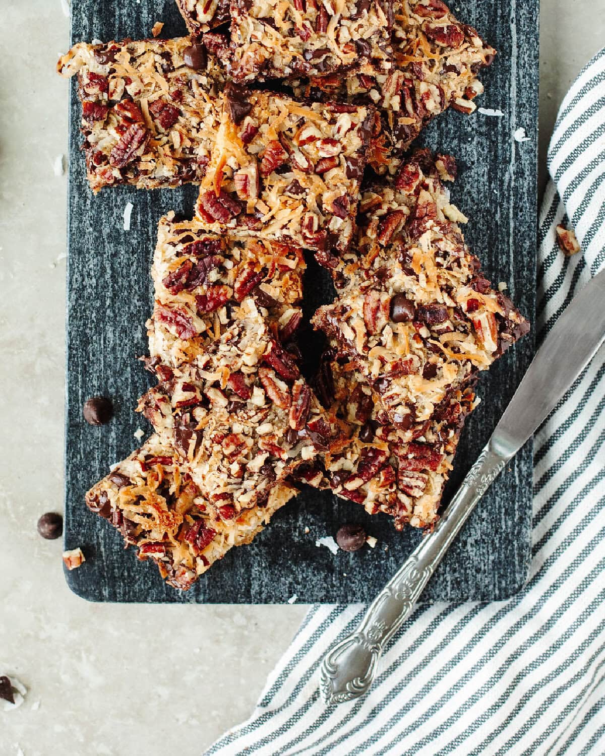 sliced magic cookie bars with a knife on a serving platter.