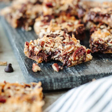 Eagle Brand Magic Cookie Bars sliced on a platter and a bite taken out of one.
