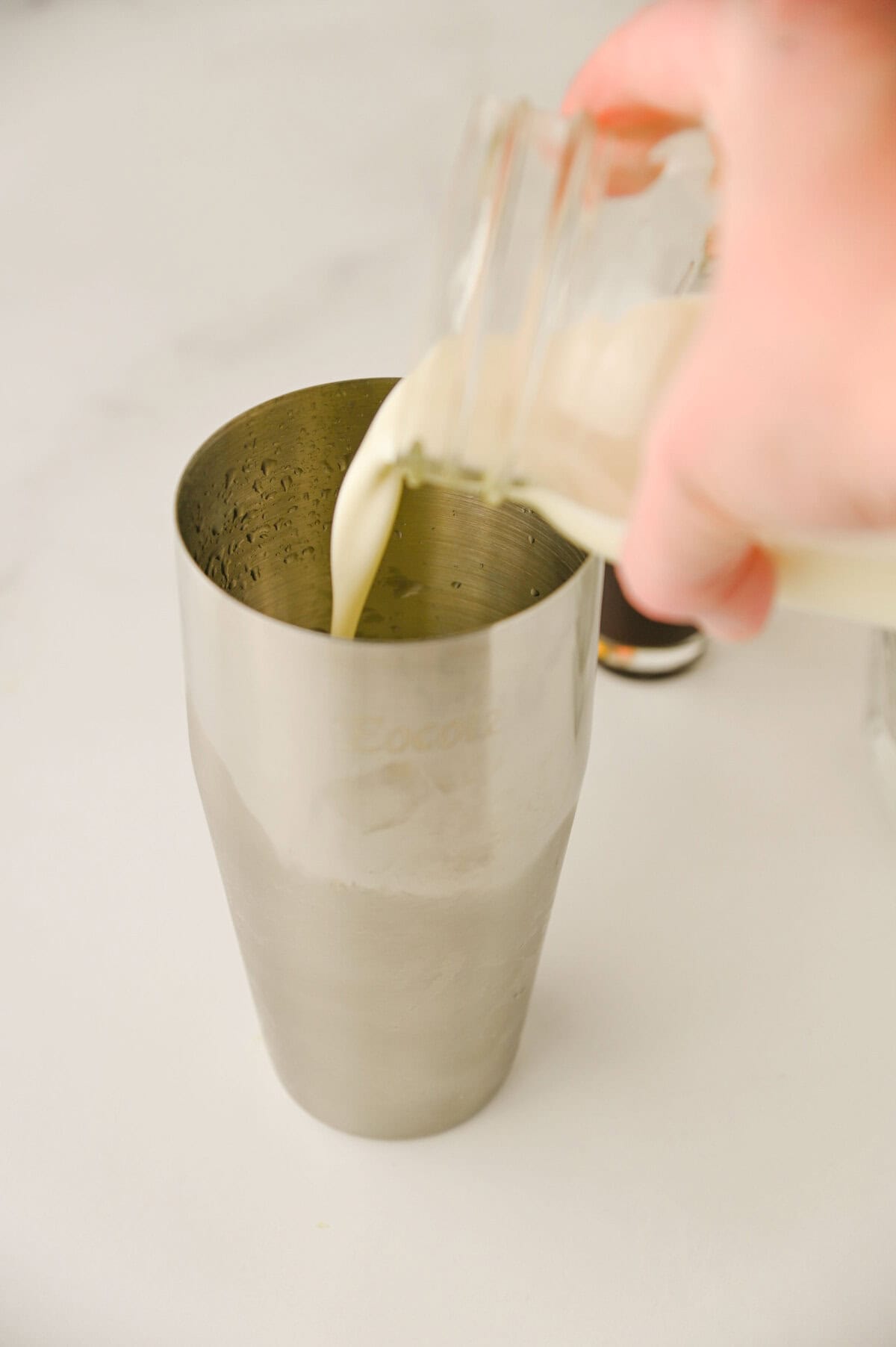 cream poured into a cocktail shaker.
