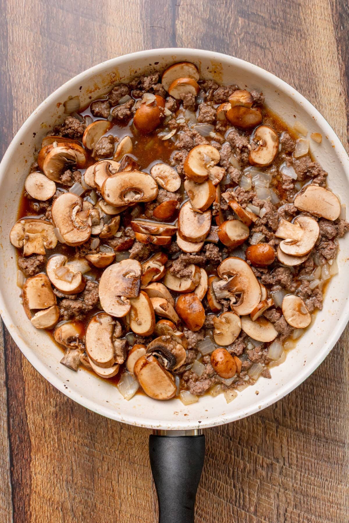 Ground beef, garlic, onion, and beef broth simmering in a skillet.