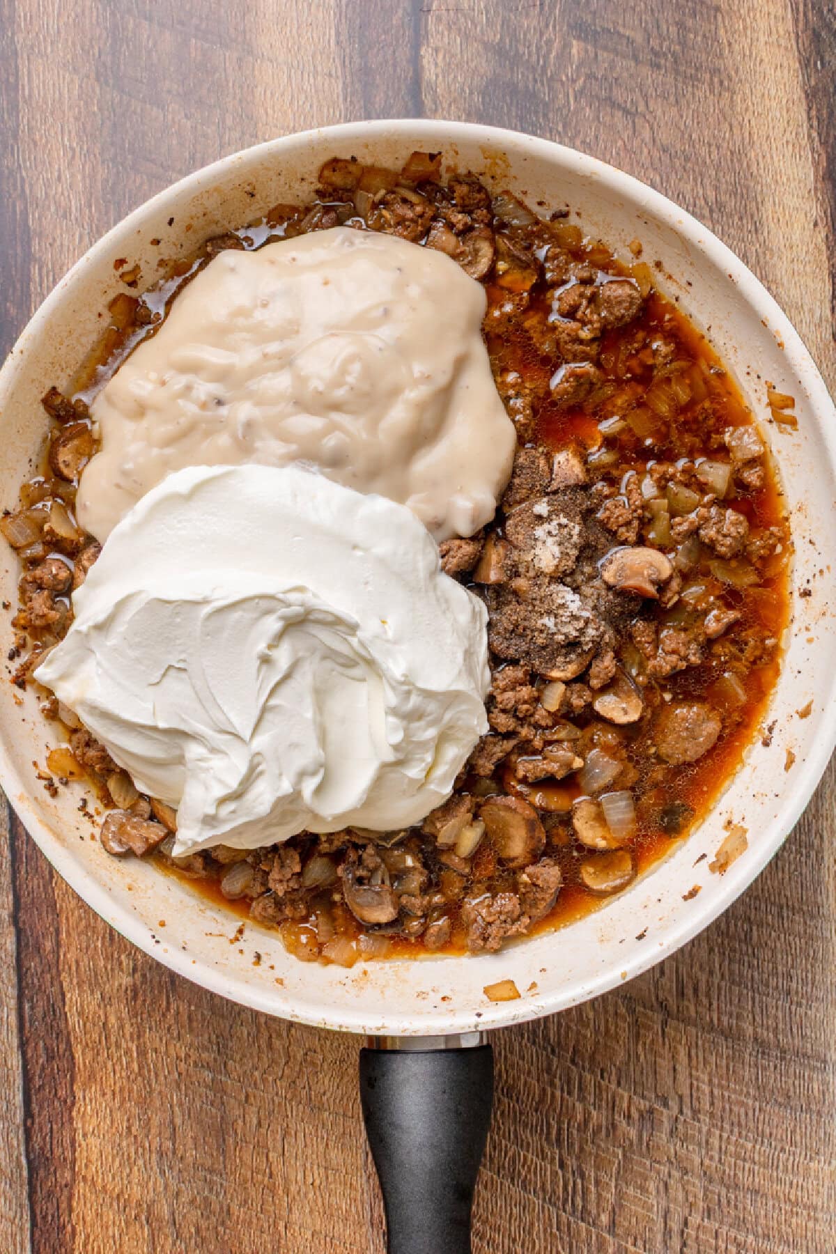 Sour cream and cream of mushroom soup added to a ground beef mixture with salt, pepper, garlic, onion, and beef broth.