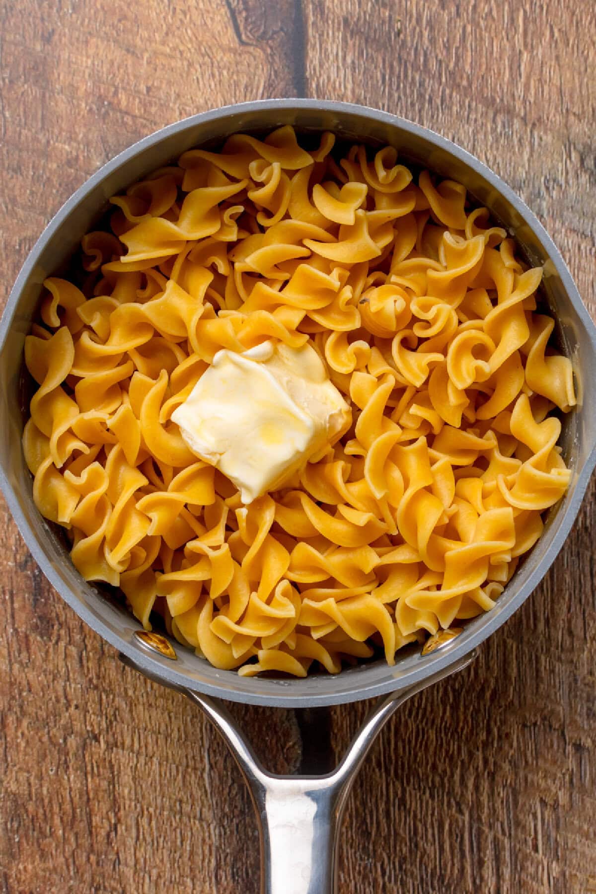 Egg noodles cooked in a pot with some melted butter.