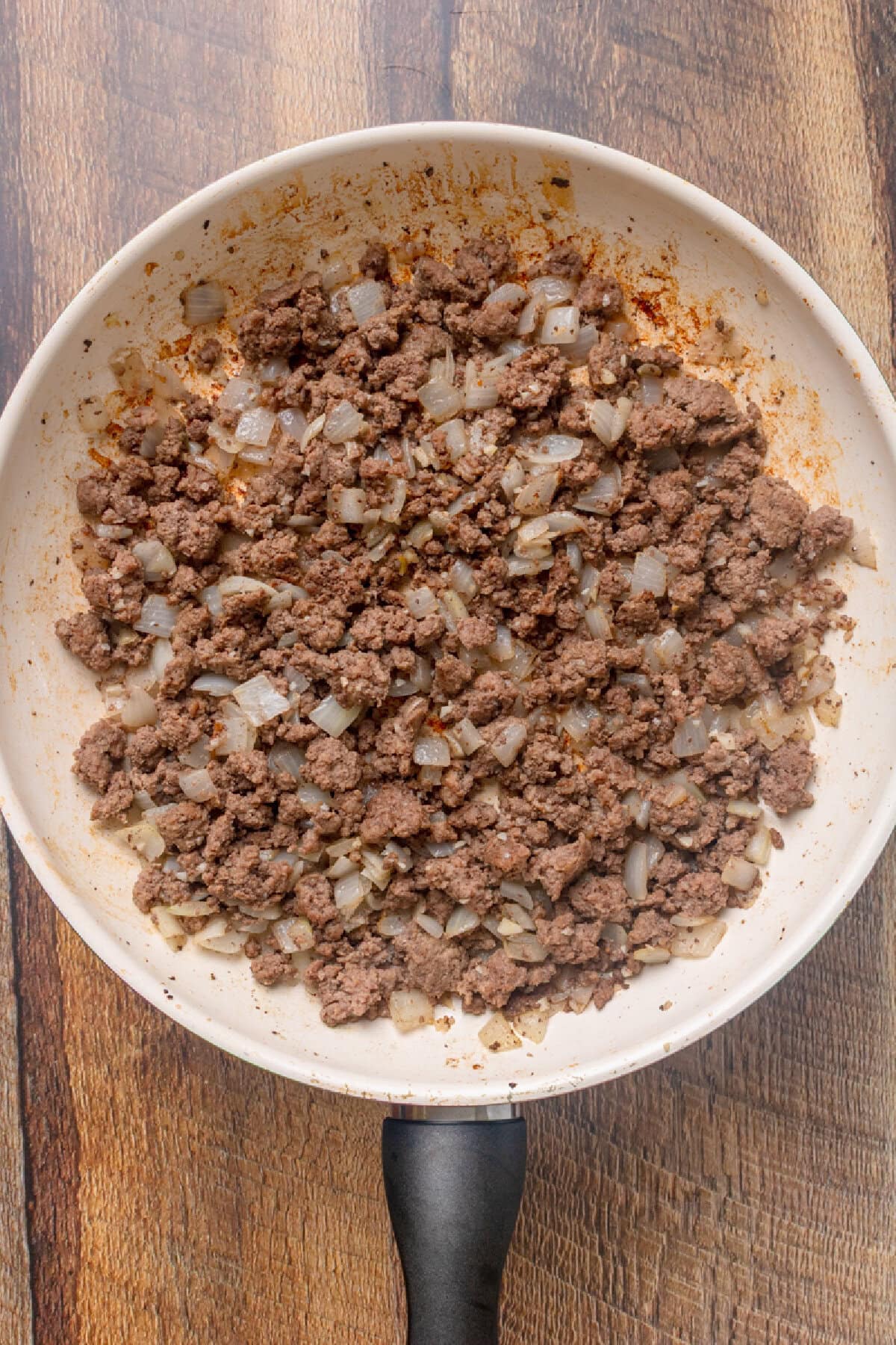 Ground beef cooked with garlic and onion in a skillet.