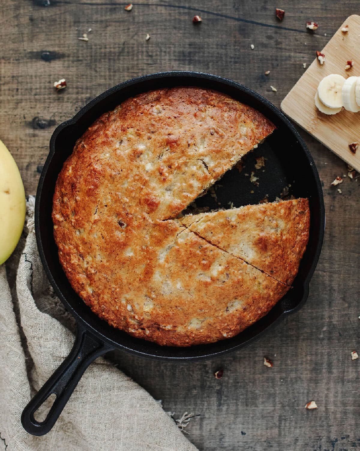 Baked cast iron skillet banana bread with a slice removed showing soft, moist center.