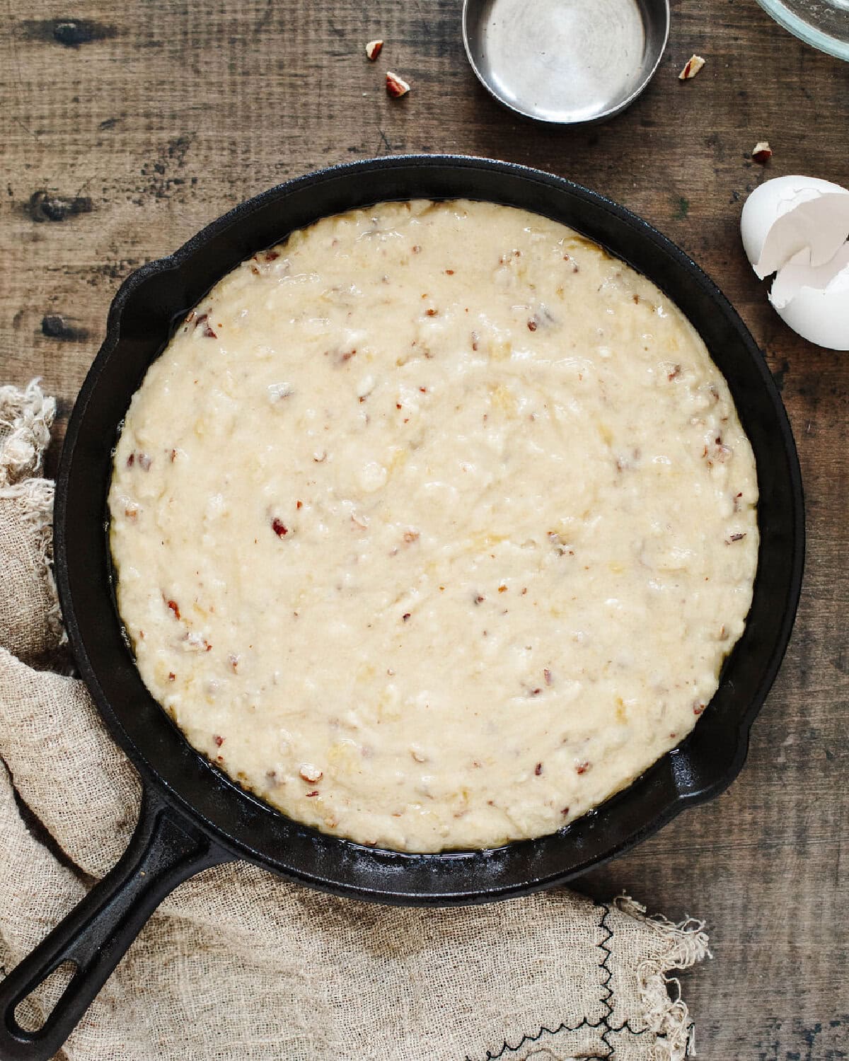 Banana bread batter spread evenly in a greased cast iron skillet before baking.