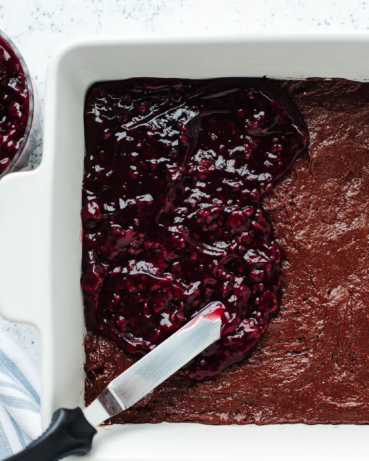 Raspberry pie filling spread over  batter in a baking dish.