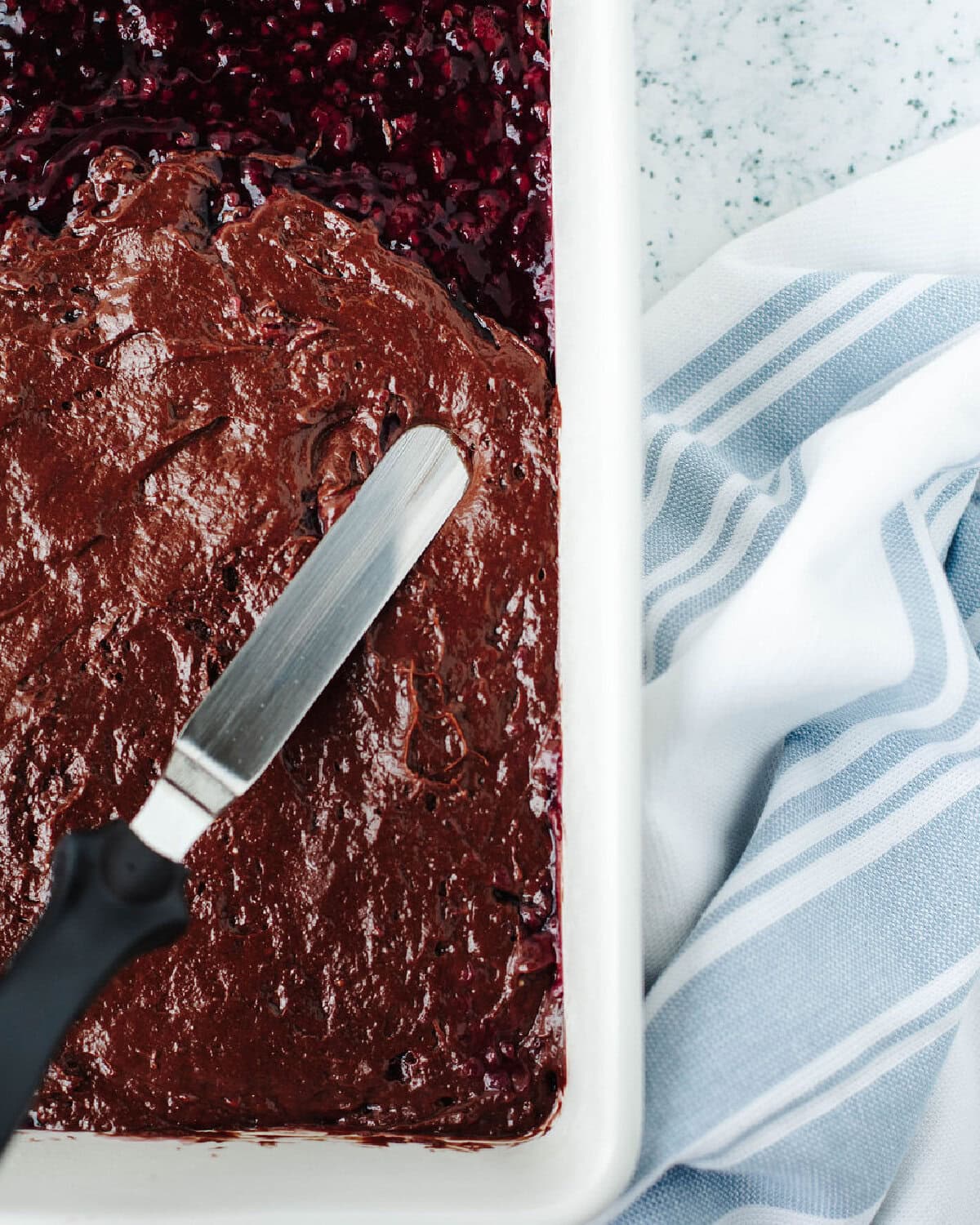 Chocolate batter spread over raspberry pie filling before baking.
