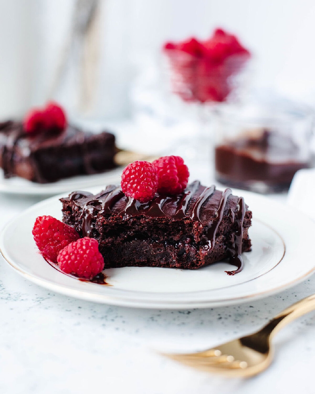 Serving of warm chocolate raspberry dump cake with hot fudge drizzle and fresh raspberries.