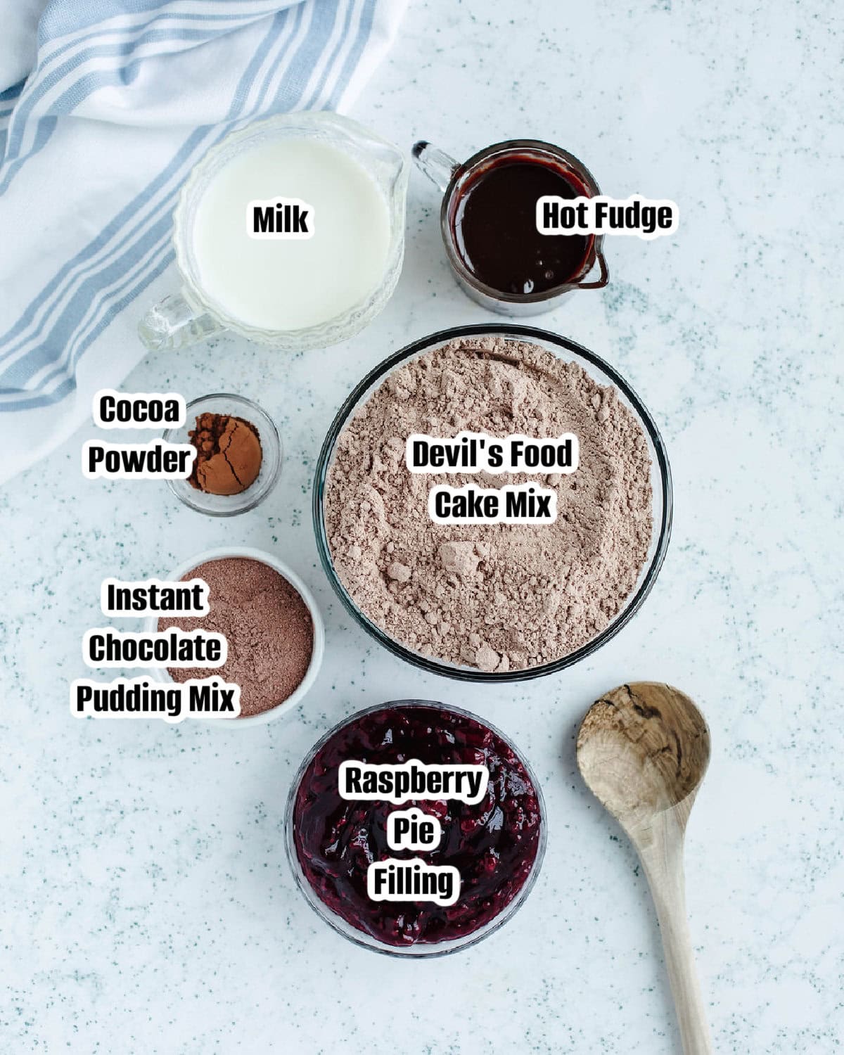 Ingredients needed to make chocolate raspberry dump cake including cake mix, pudding mix, milk, cocoa powder, and raspberry pie filling.