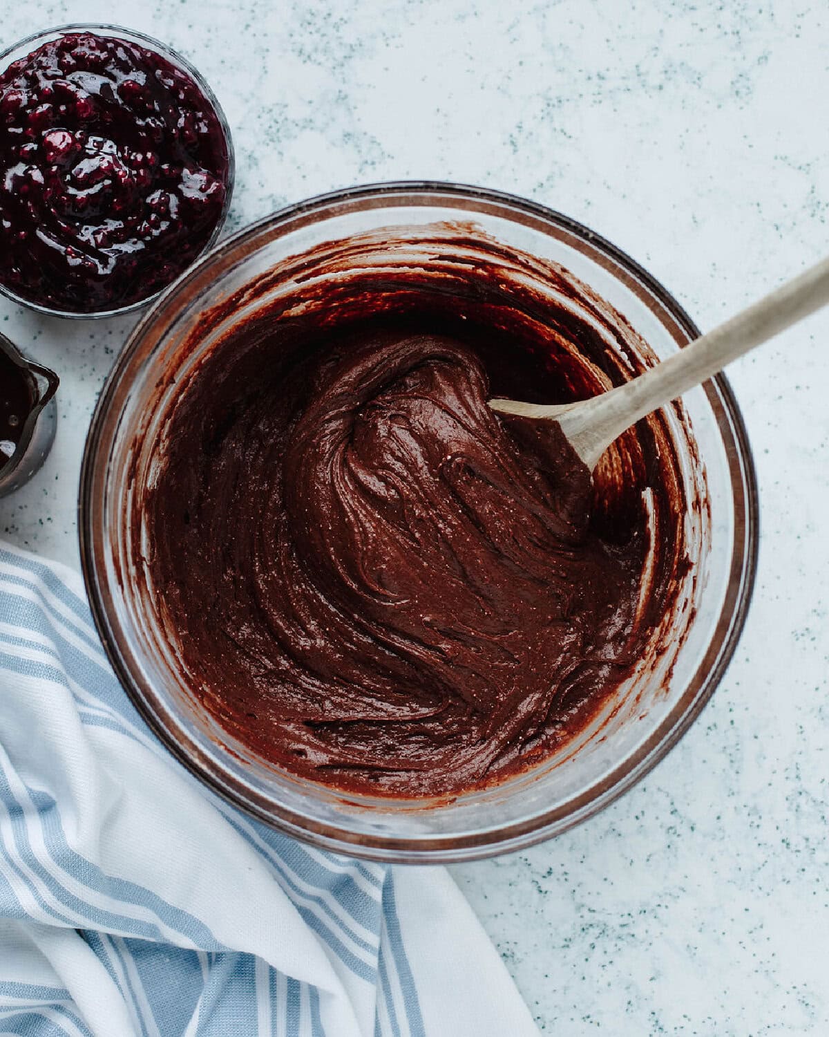 Chocolate cake batter mixed with pudding and cocoa powder in a glass bowl.