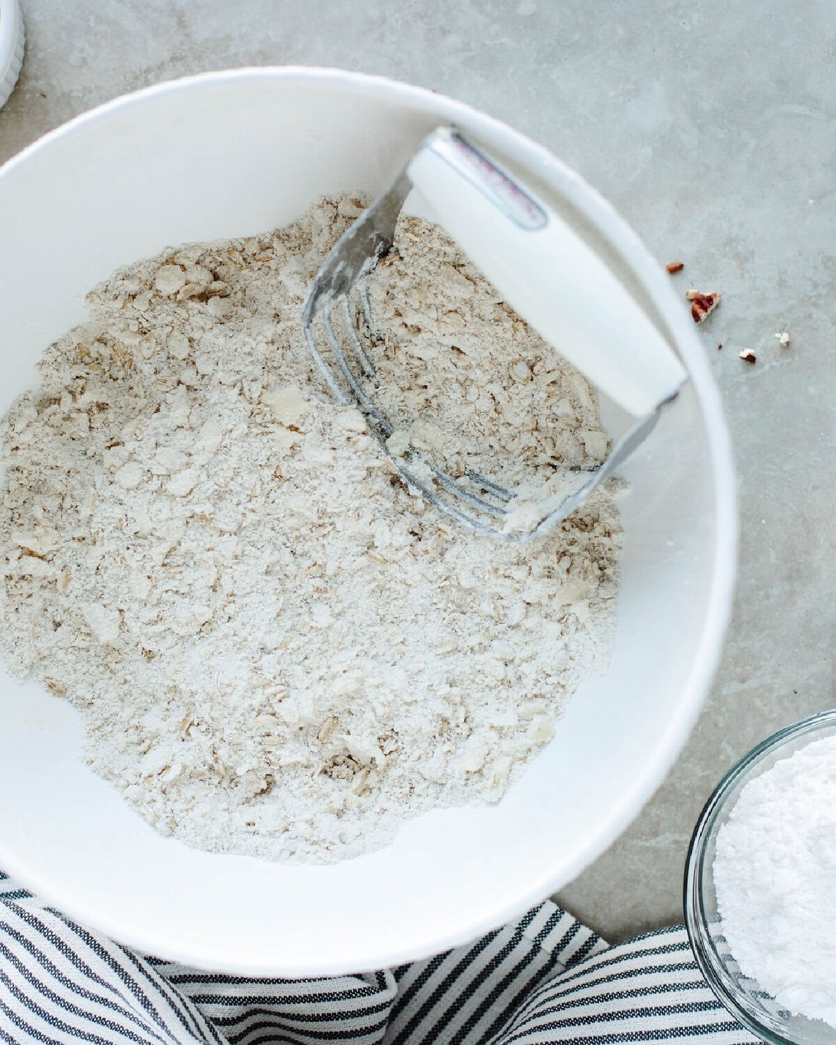 cold butter being mixed into dry ingredients using a pastry blender in a mixing bowl.