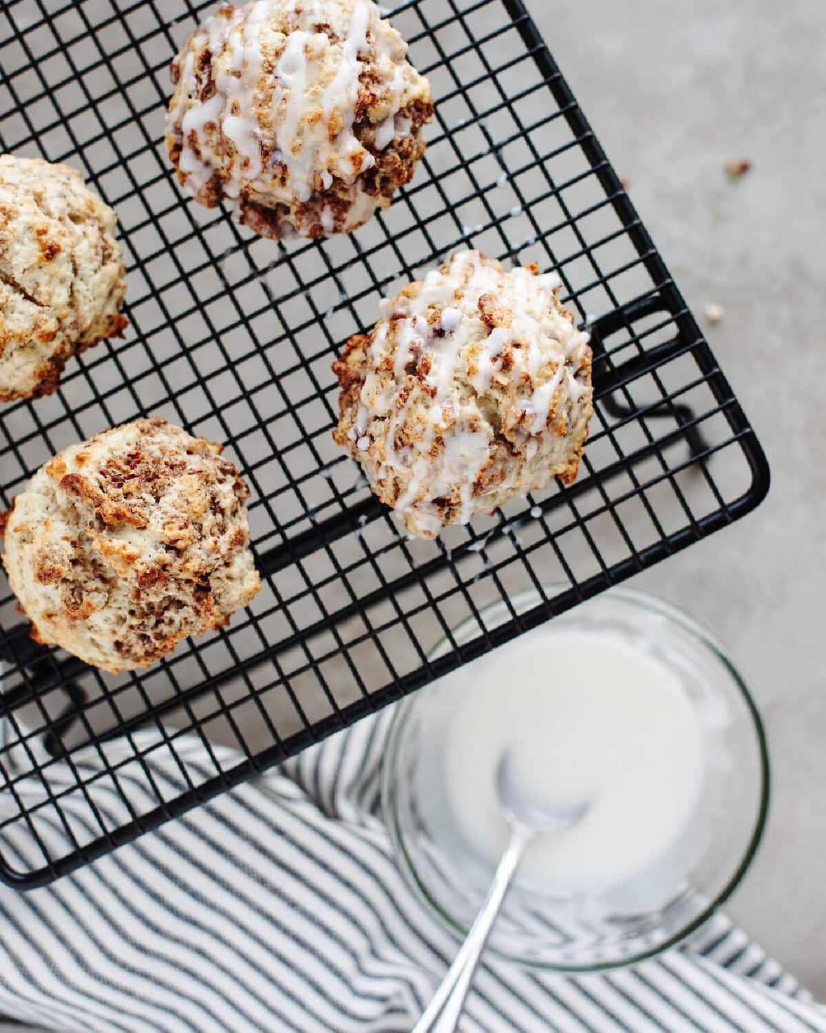 icing drizzled on top of cinnamon scones on a wire rack.