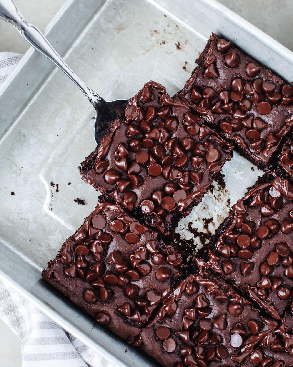 a spatula scooping out a piece of chocolate dump cake with melted chocolate chips on top.