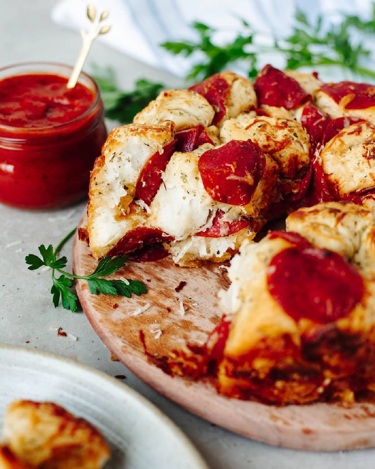 an up close look at pizza monkey bread on a wood serving board with a side of marinara sauce.