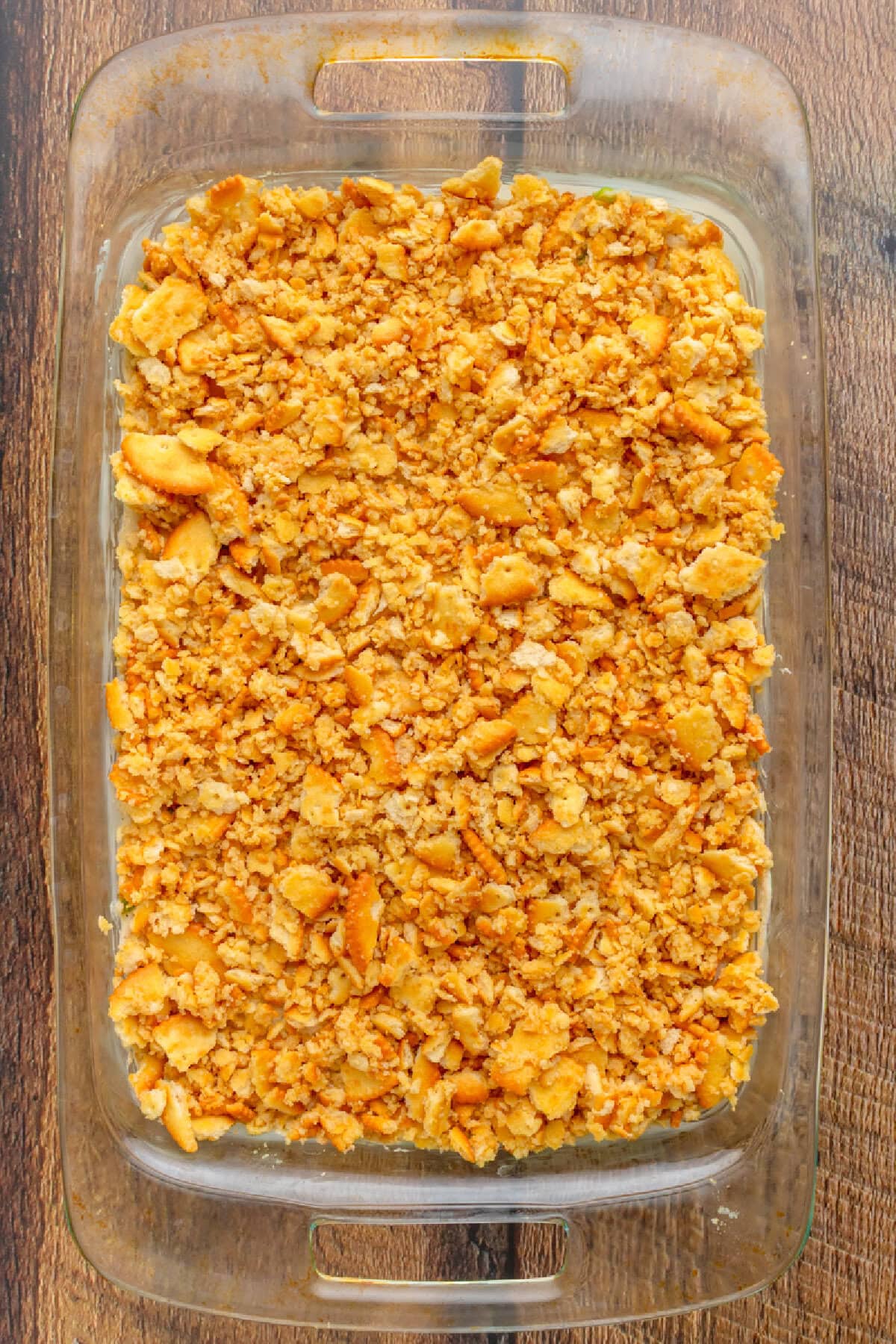Sprinkling buttery ritz cracker topping over chicken casserole before baking.
