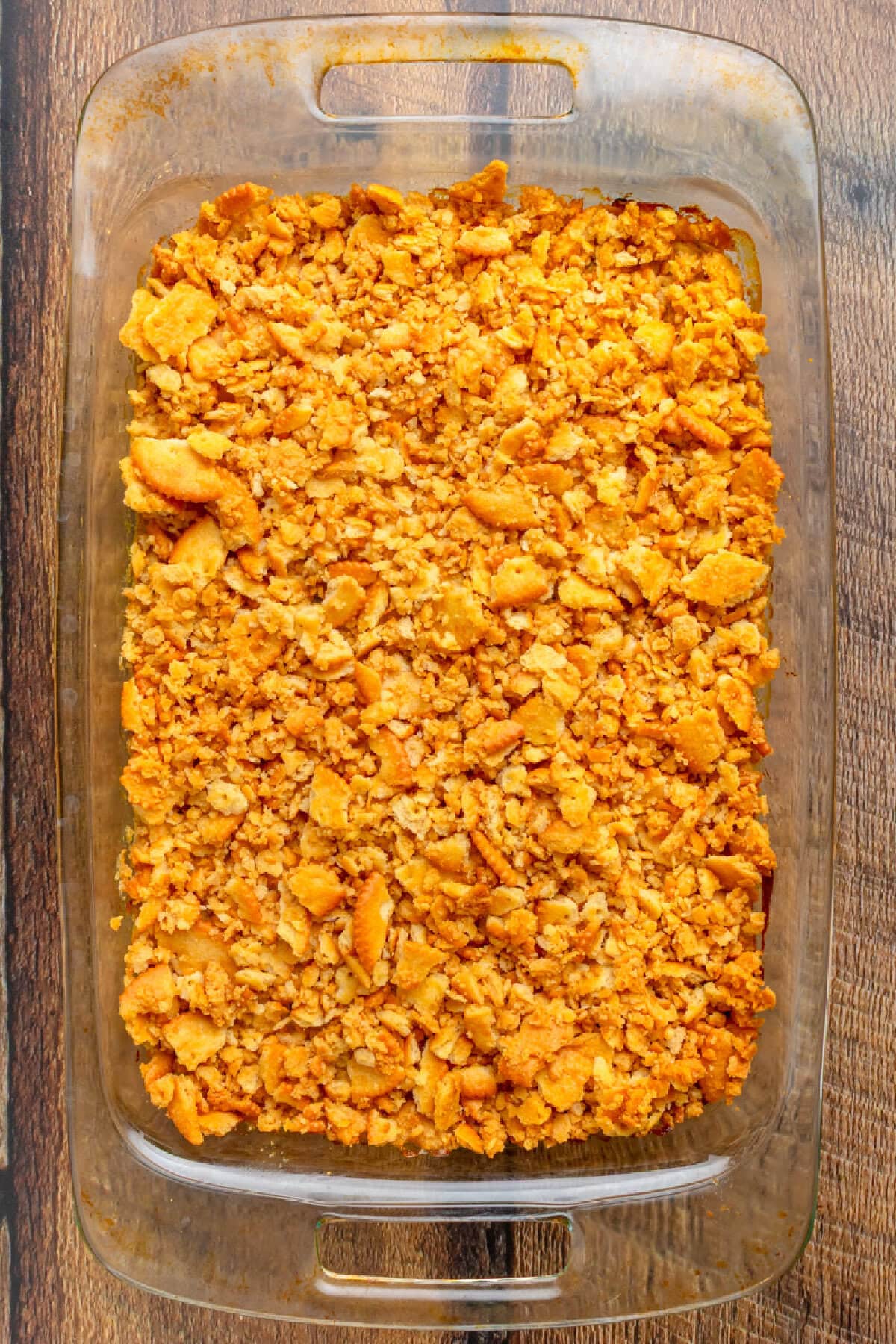 Freshly baked chicken casserole with golden ritz cracker topping in a glass baking pan.