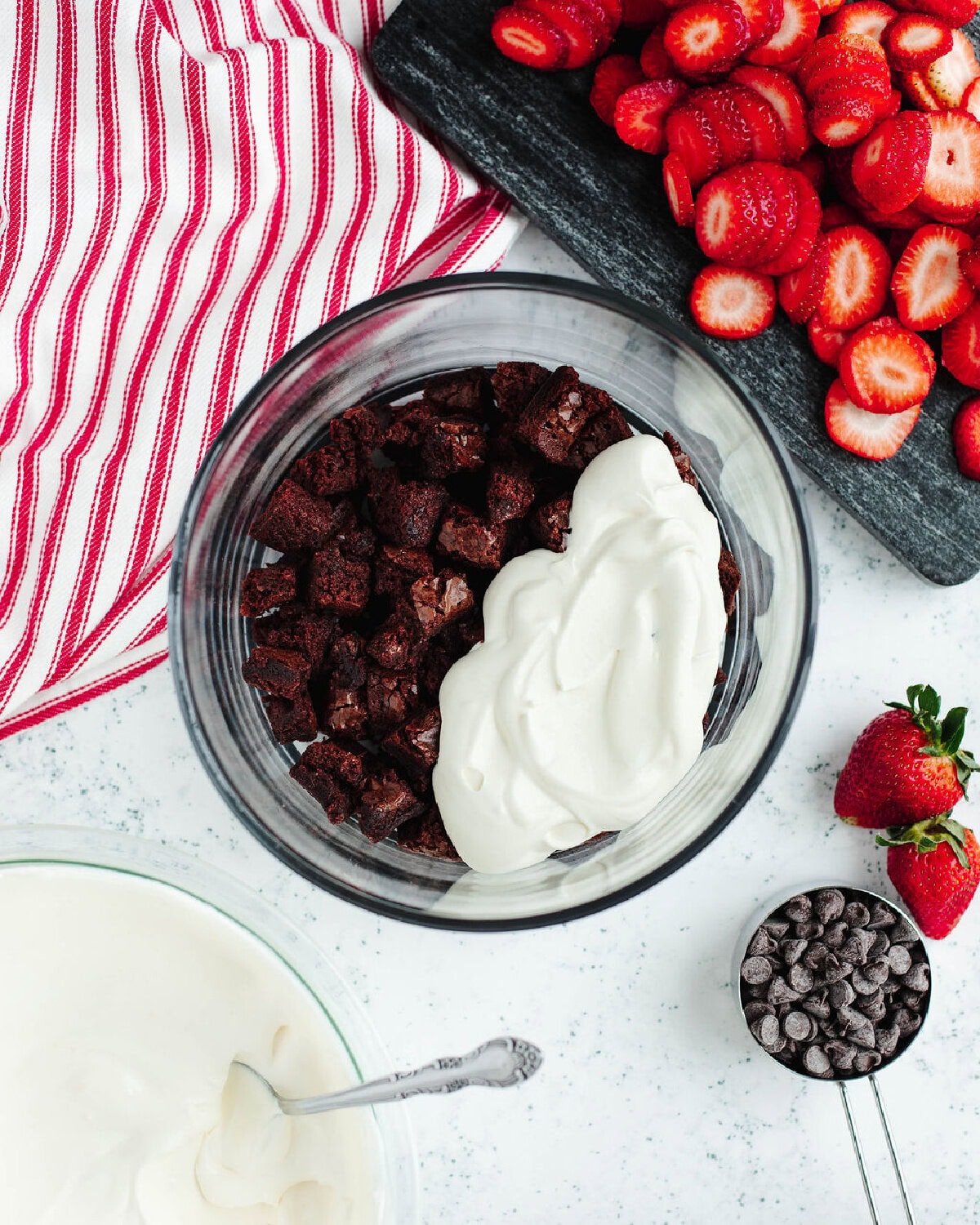 A creamy vanilla pudding mixture spread over brownie bites in a glass trifle bowl.