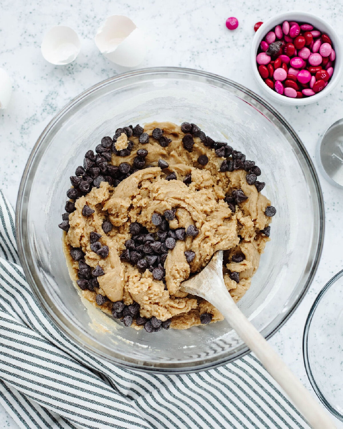 Egg yolks folded into cookie dough in a glass mixing bowl.