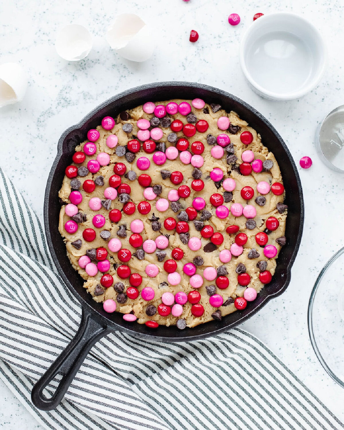 Cookie dough spread into a cast iron skillet and seasonal m & m's sprinkled on top.