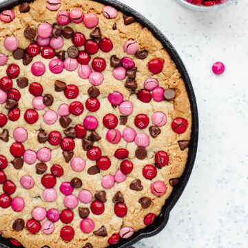 Red and pink M & M's sprinkled throughout a chocolate chip cookie skillet.